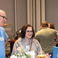 Three people at event, standing around table and chatting